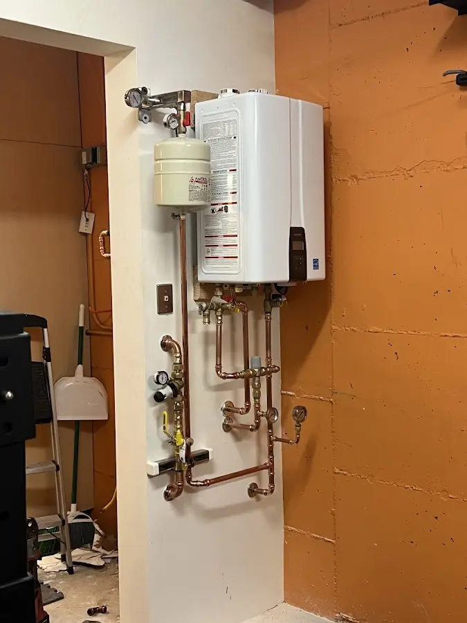 Plumbing technician inspecting water heater connections in Grand Ledge